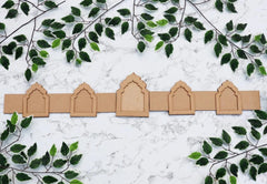 Row of cardboard arches on a marble surface with green leaves