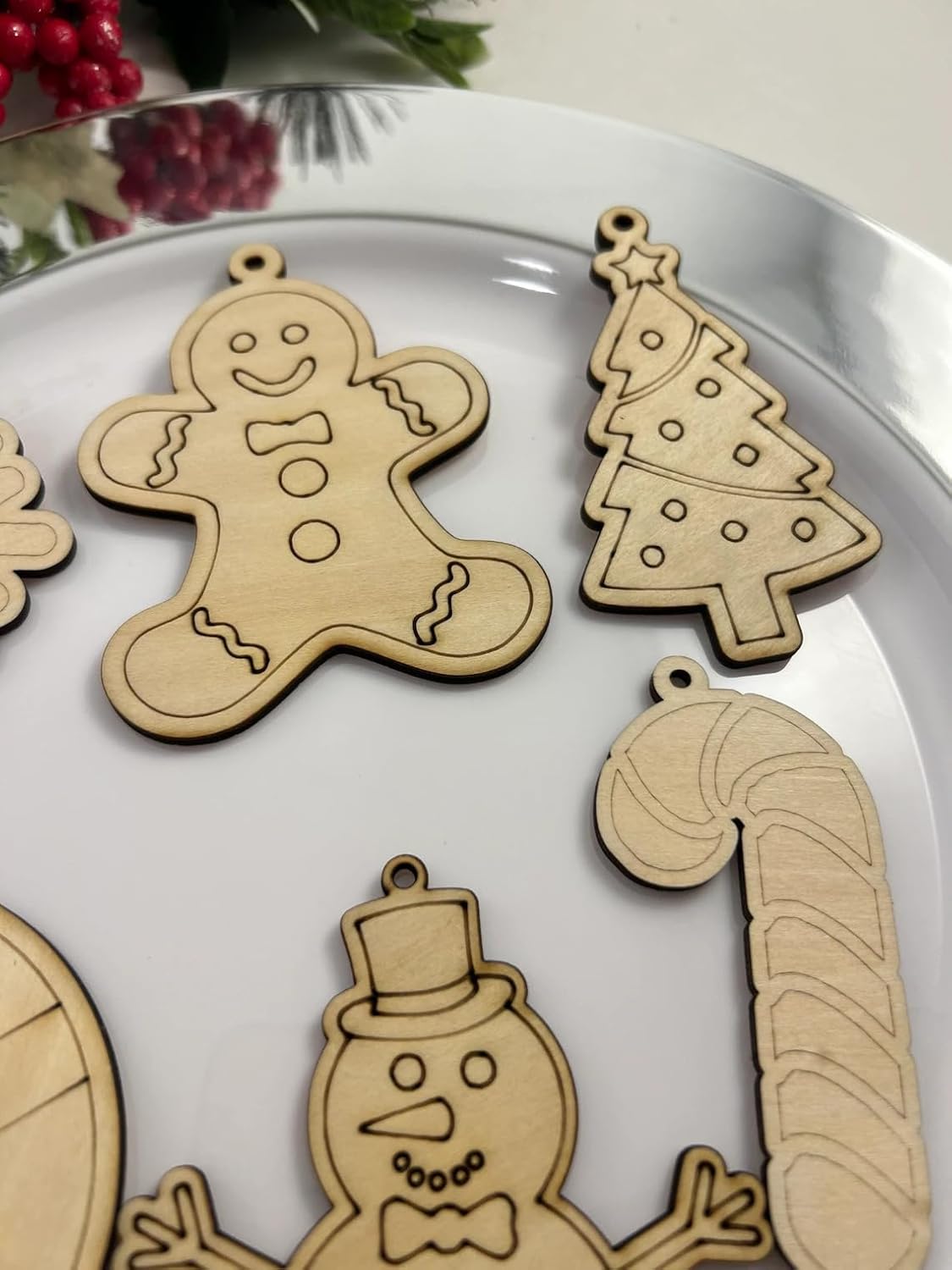 Wooden Christmas ornaments including a gingerbread man, candy cane, and snowman on a white plate.