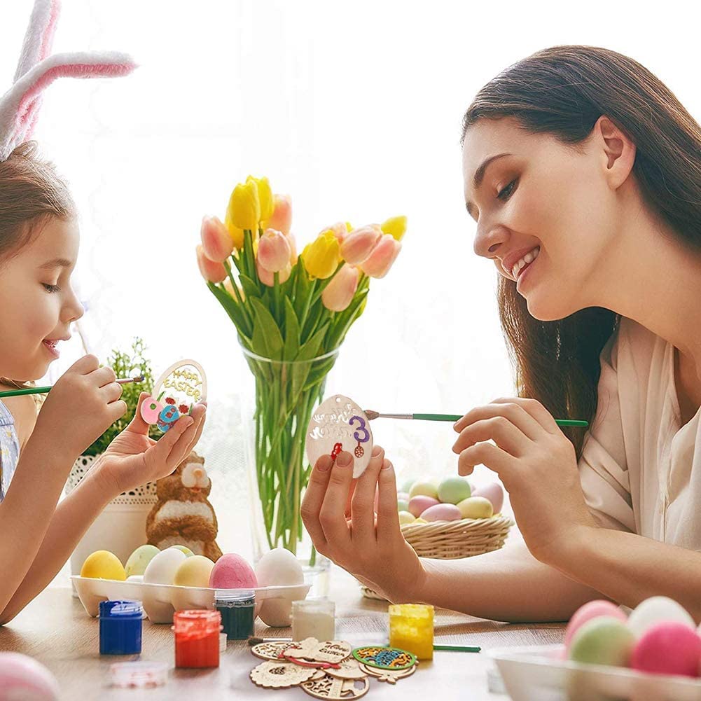 Woman and child painting Easter eggs with a vase of tulips in the background