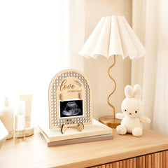 Decorative ultrasound frame on a table with a lamp and plush toy in the background
