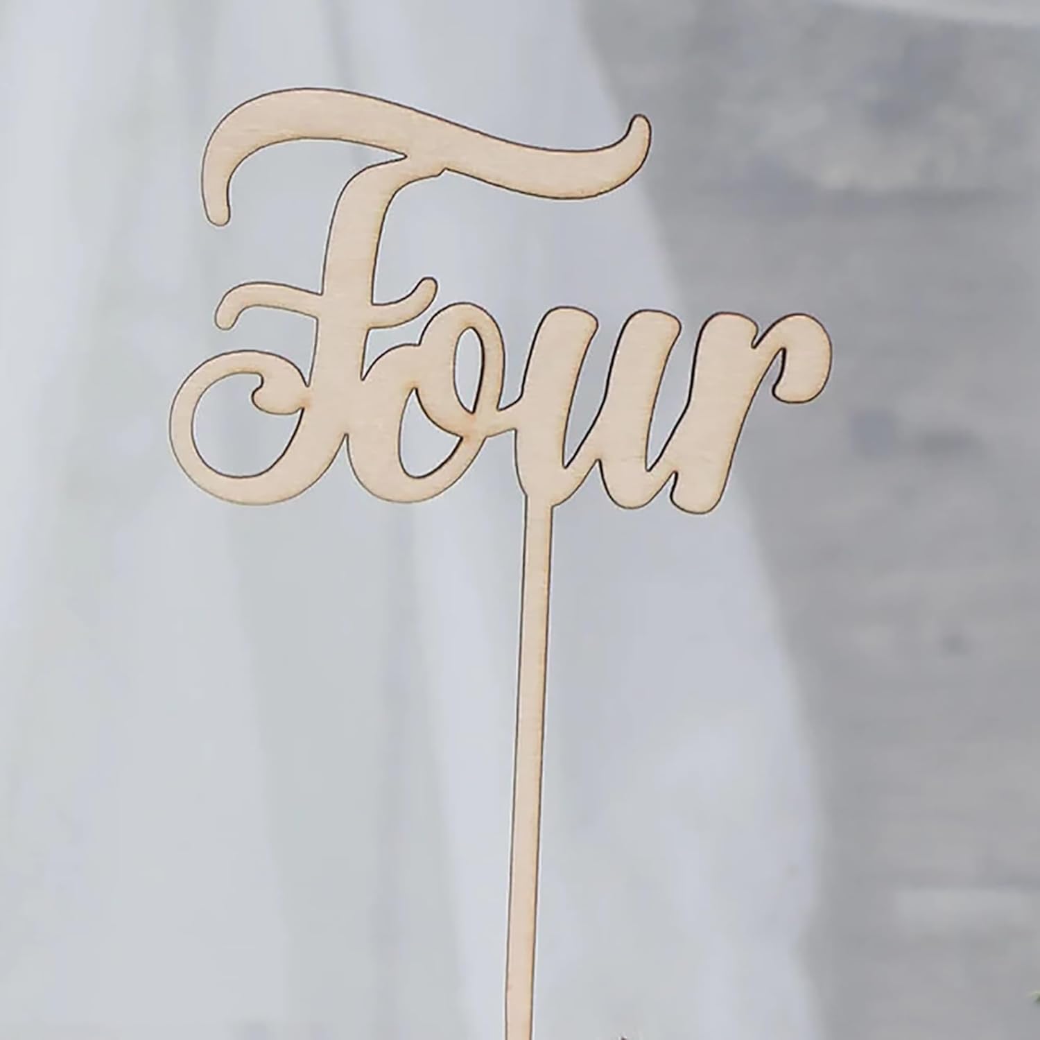 Wooden 'Four' cake topper on a light background