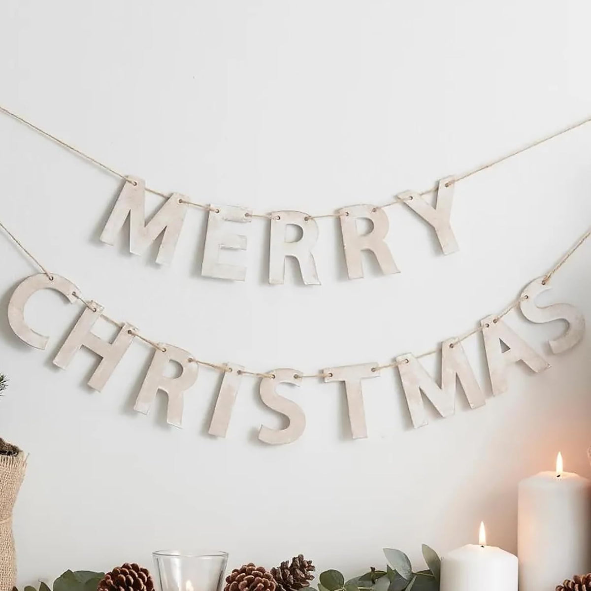 Merry Christmas banner with candles and greenery on a white wall