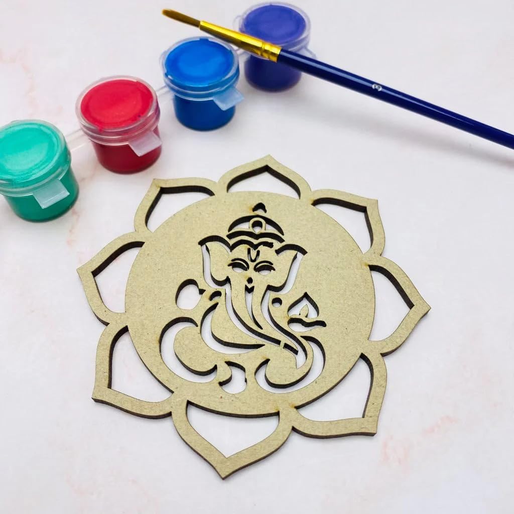 Decorative wooden cutout with Ganesha design on a white surface with paint containers and a brush.