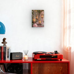 Red record player on a wooden shelf with books, a candle, and a small statue.