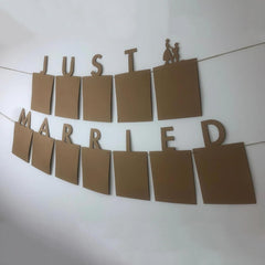 Brown paper 'Just Married' banner with a couple silhouette on a white background