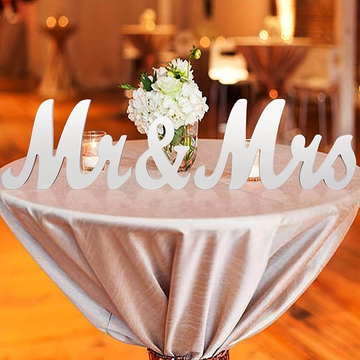 Decorative table setting with 'Mr & Mrs' sign and flowers on a blurred background