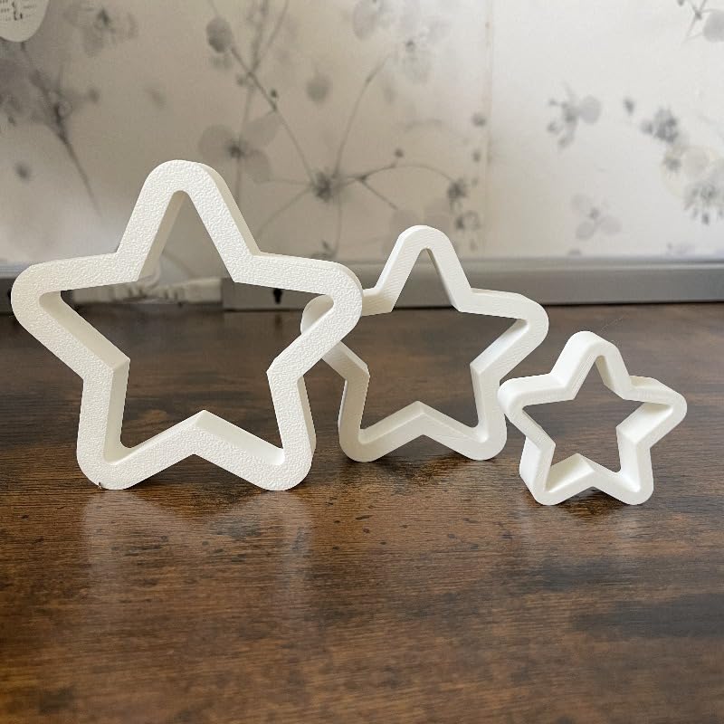 Set of star-shaped cookie cutters on a wooden surface with a floral-patterned fabric background.