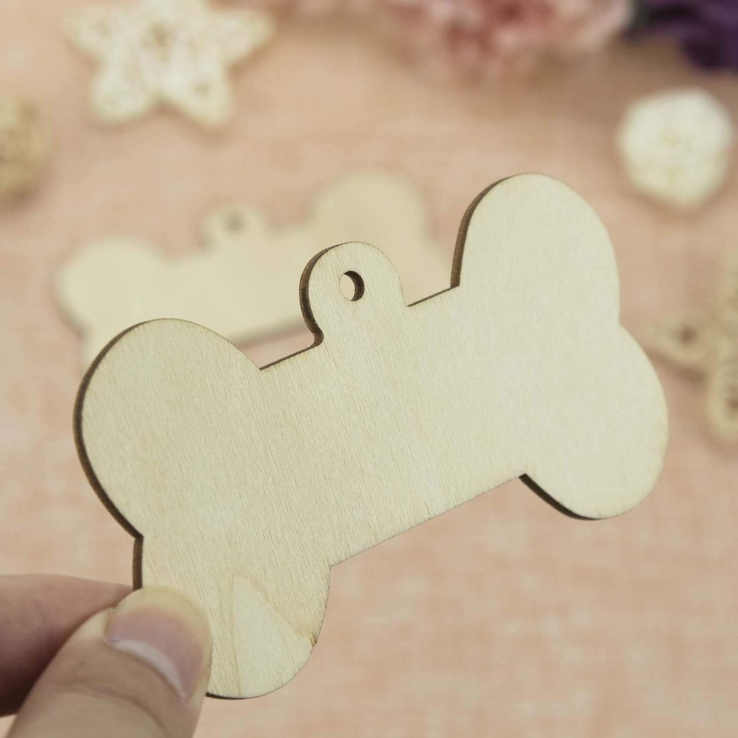 Wooden bone-shaped tag held by a hand with a floral background