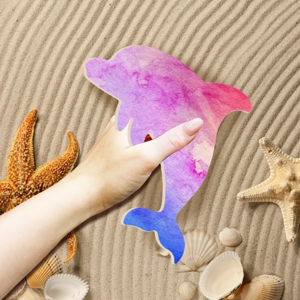 Colorful dolphin-shaped object held by a hand on sand with starfish and shells.