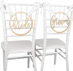 Two white chairs with gold 'bride' and 'groom' signs on a white background