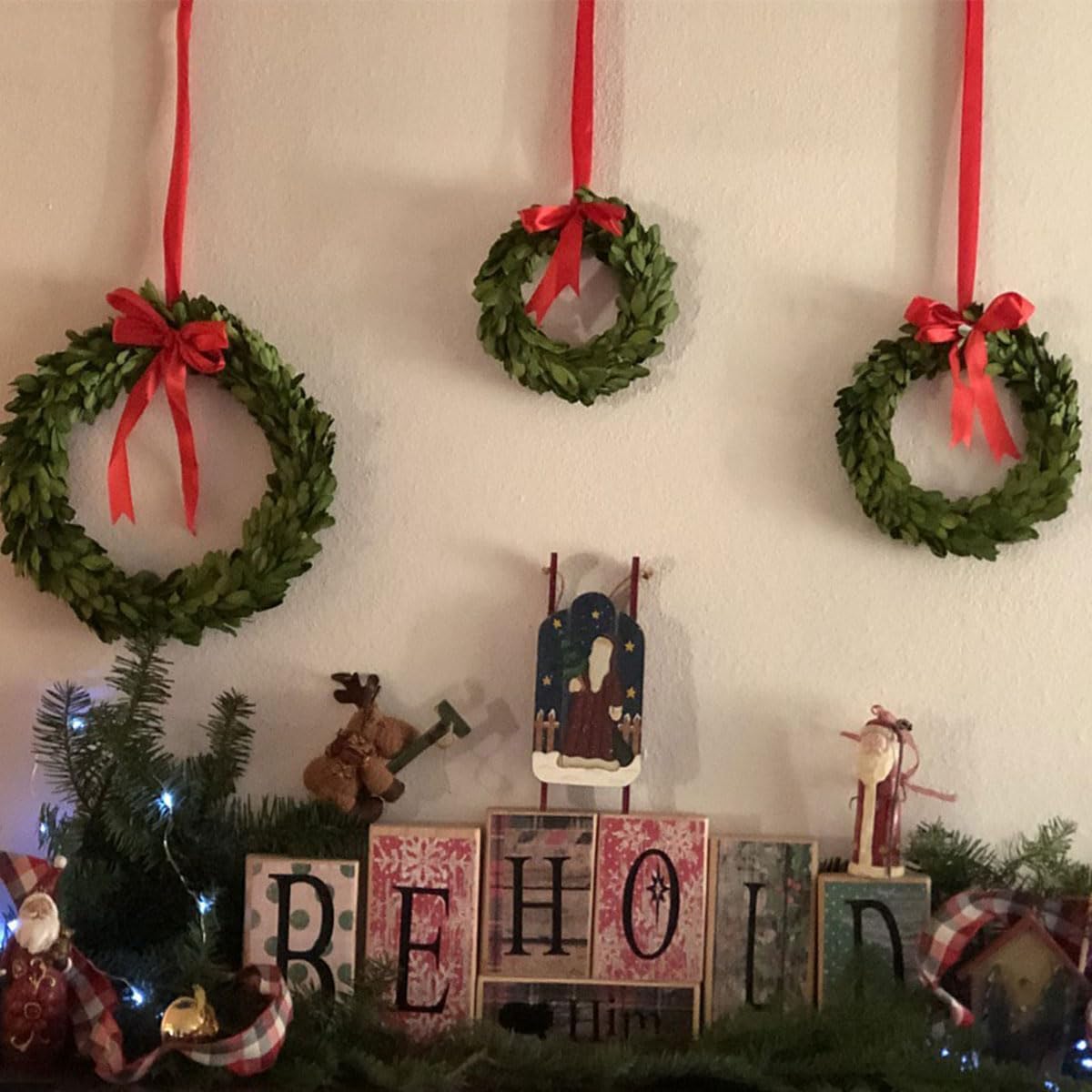 Decorative Christmas wreaths with red ribbons hanging on a wall, with 'REHOOL' sign below.