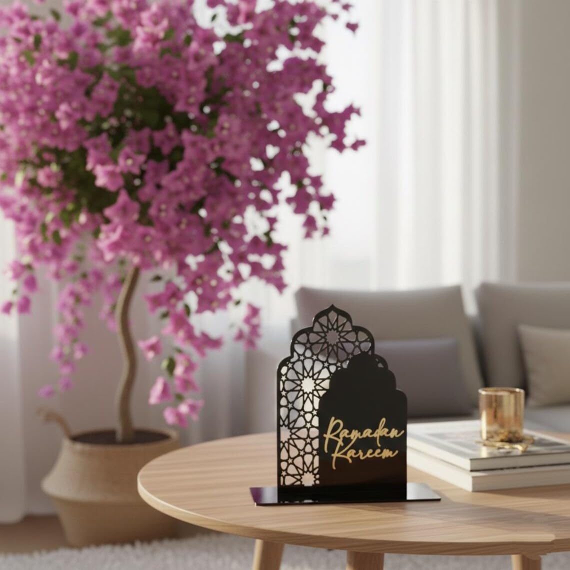 Decorative lantern with 'Ramadan Kareem' on a table with pink flowers and books in the background