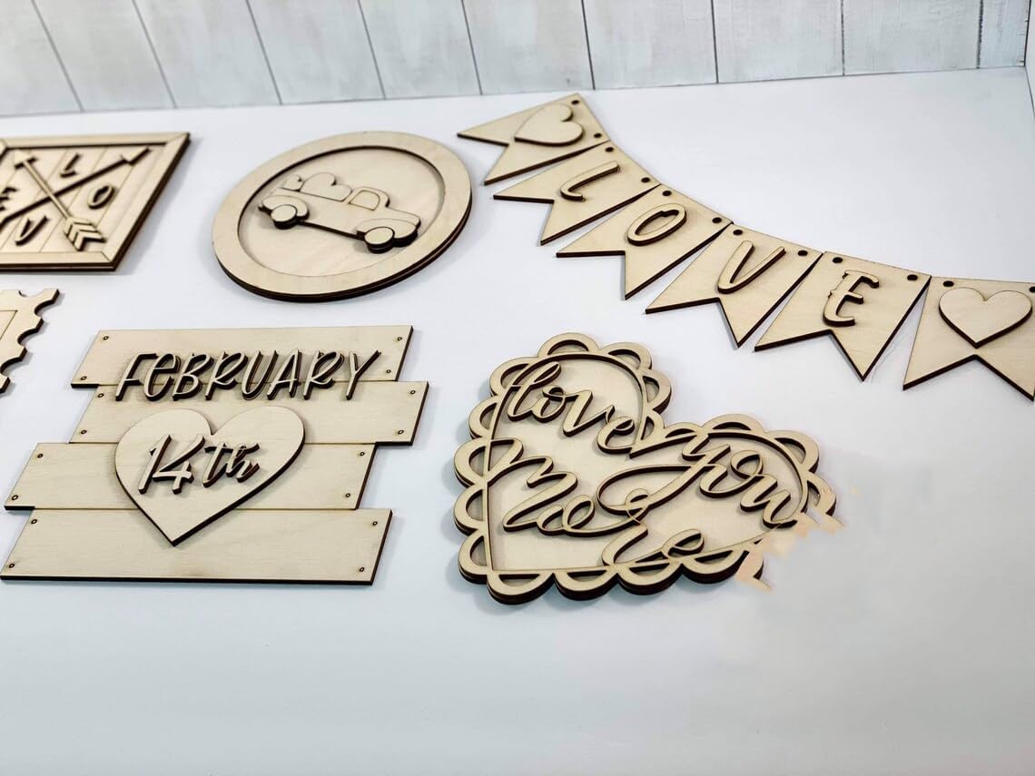 Collection of wooden decorative items including a 'LOVE' banner, heart-shaped signs, and 'FEBRUARY' plaque on a white surface.