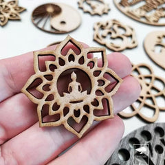 Hand holding a wooden decorative piece with intricate cut-out design, surrounded by similar pieces on a light background.