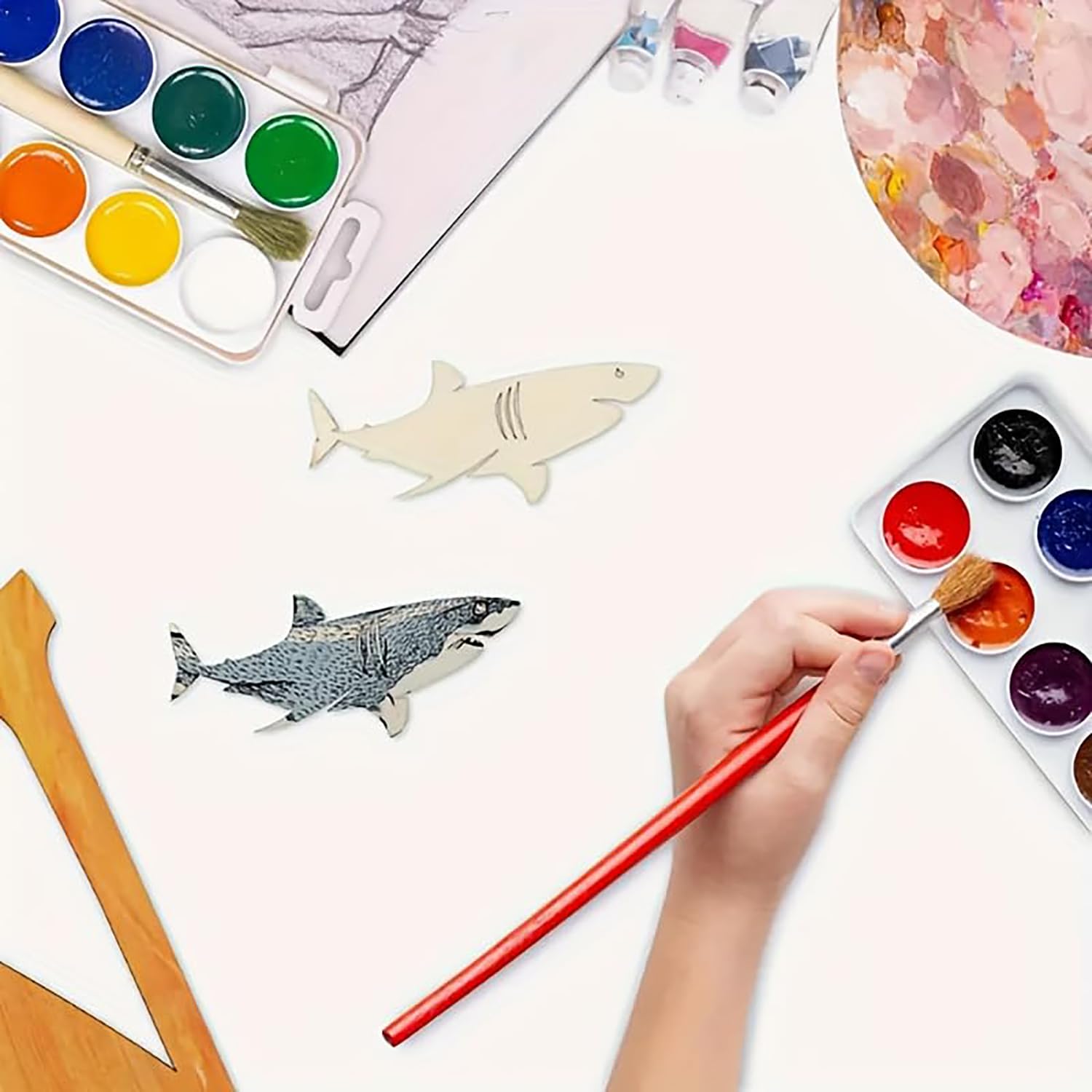 Child painting shark shapes with watercolors on a white surface