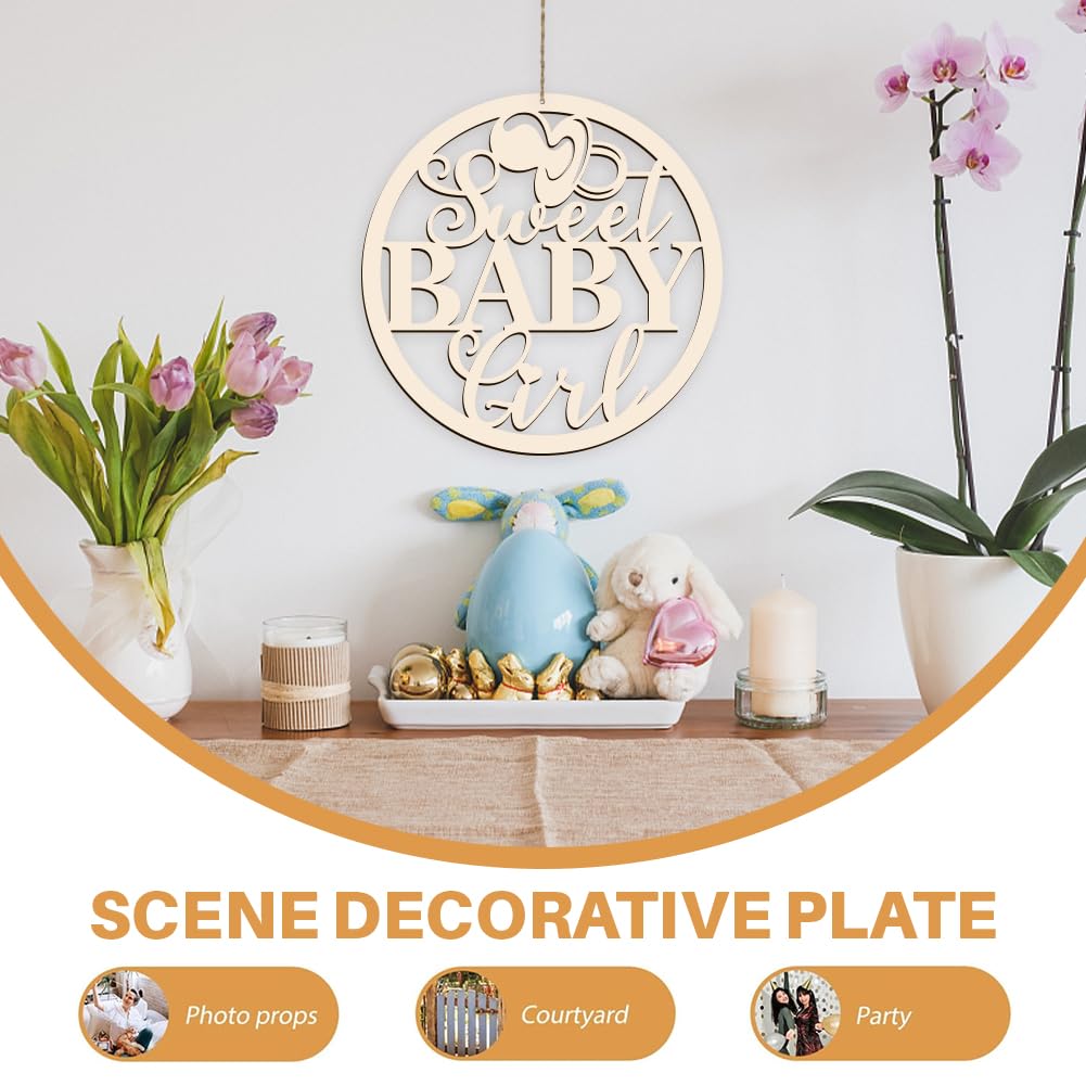 Decorative plate with 'Sweet Baby Girl' text, surrounded by baby-themed items and plants on a wooden surface.