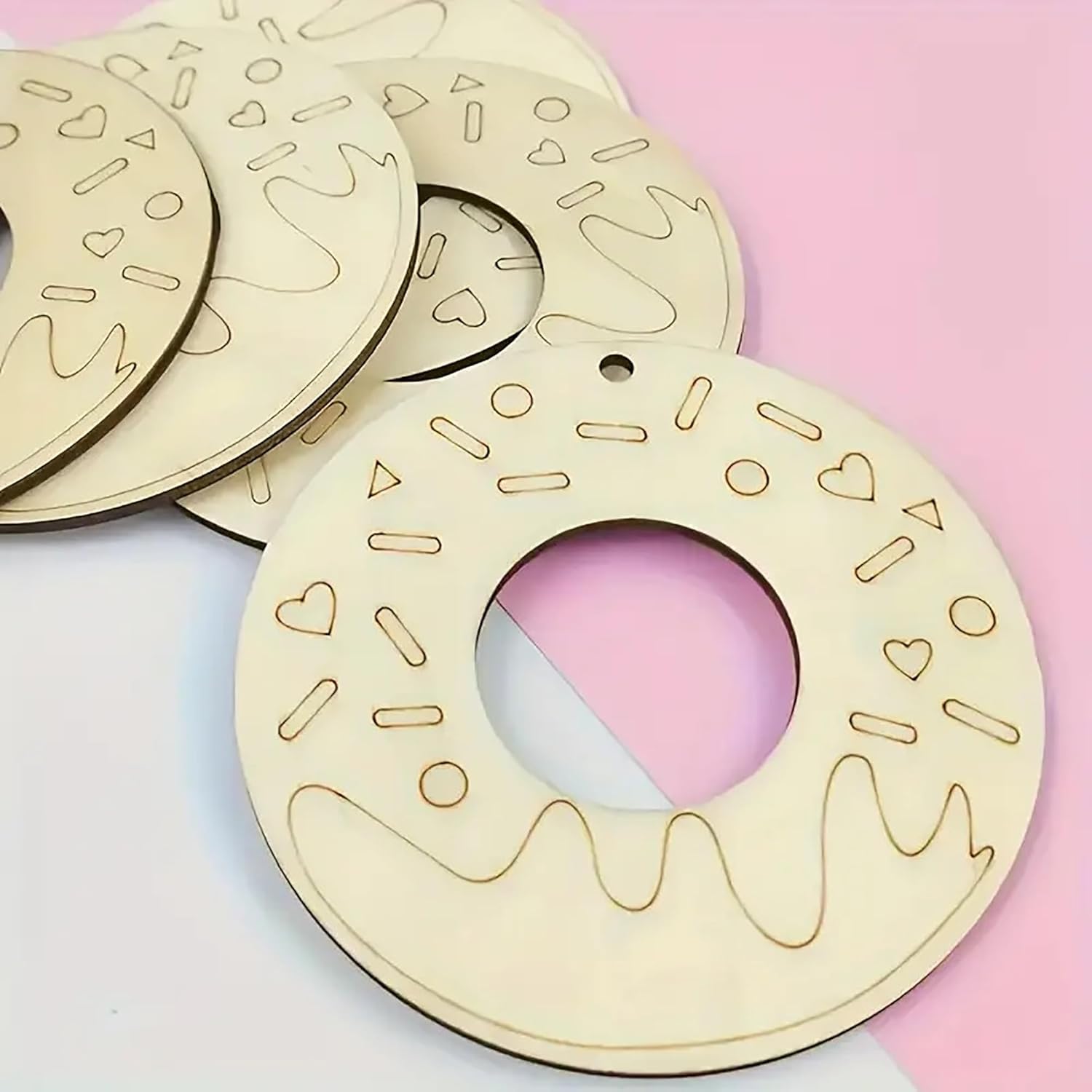 Wooden donut-shaped ornament with decorative patterns on a pink and white background