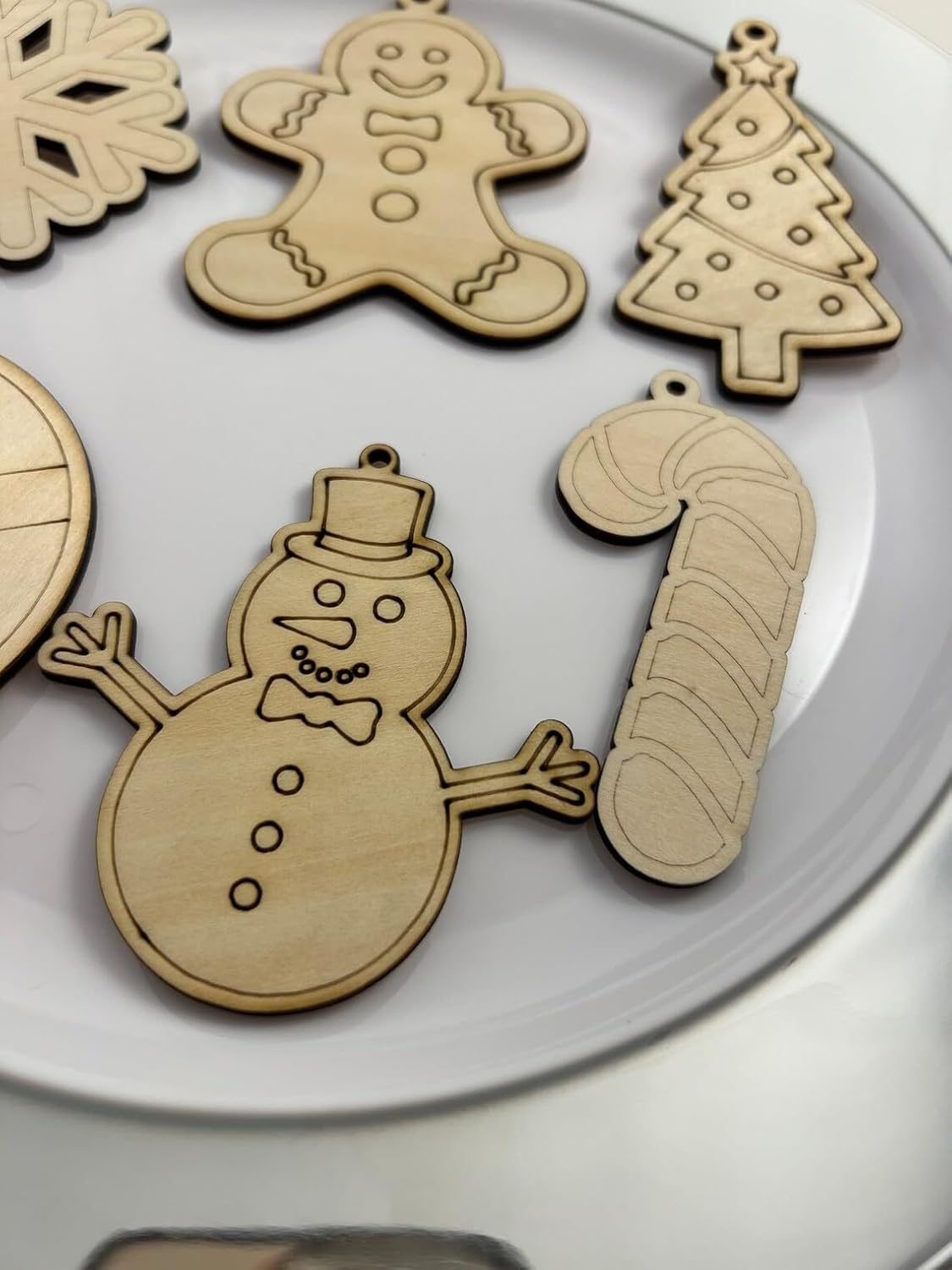 Wooden Christmas ornaments including a snowman, gingerbread man, candy cane, and tree on a white background.