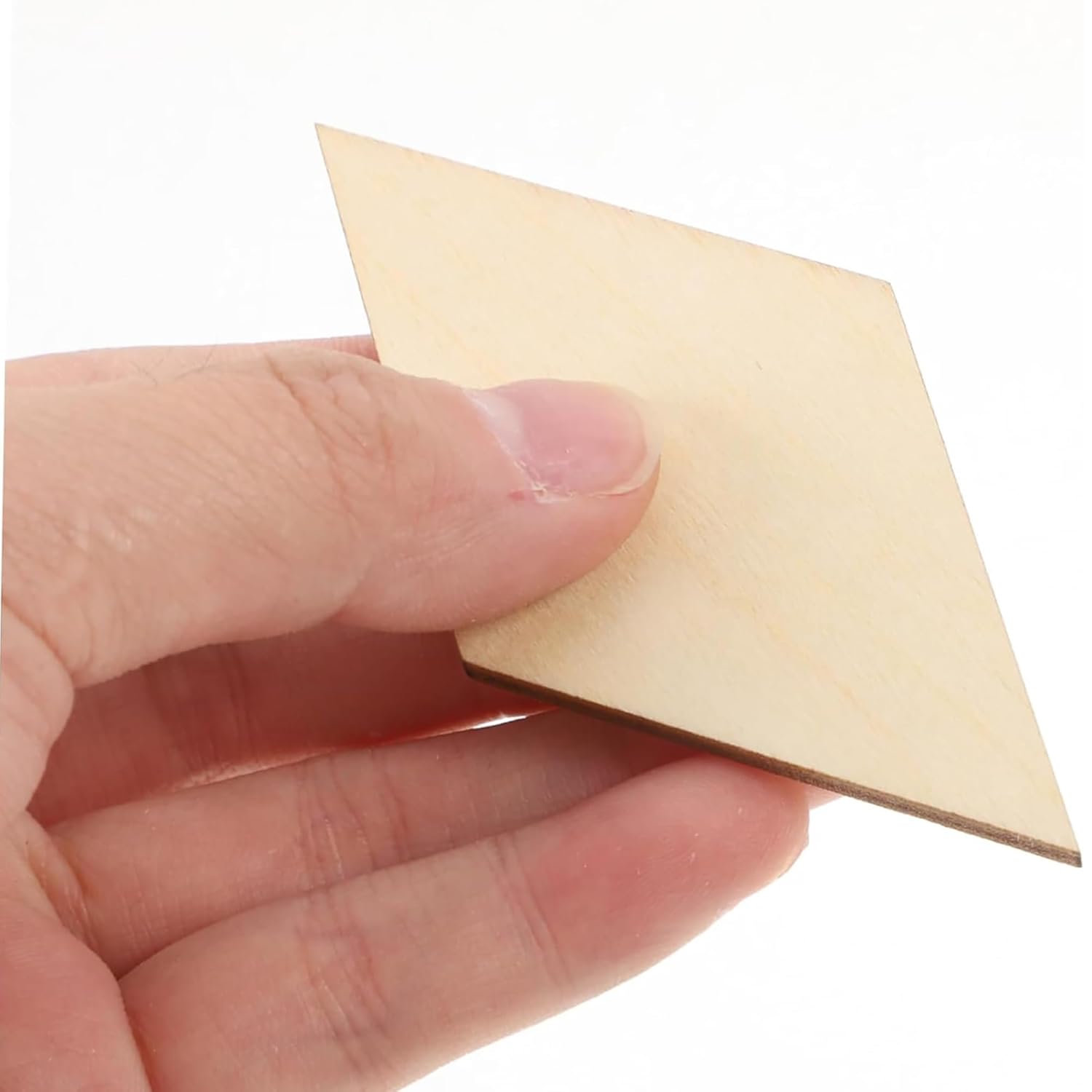 Hand holding a small beige square piece of paper against a white background