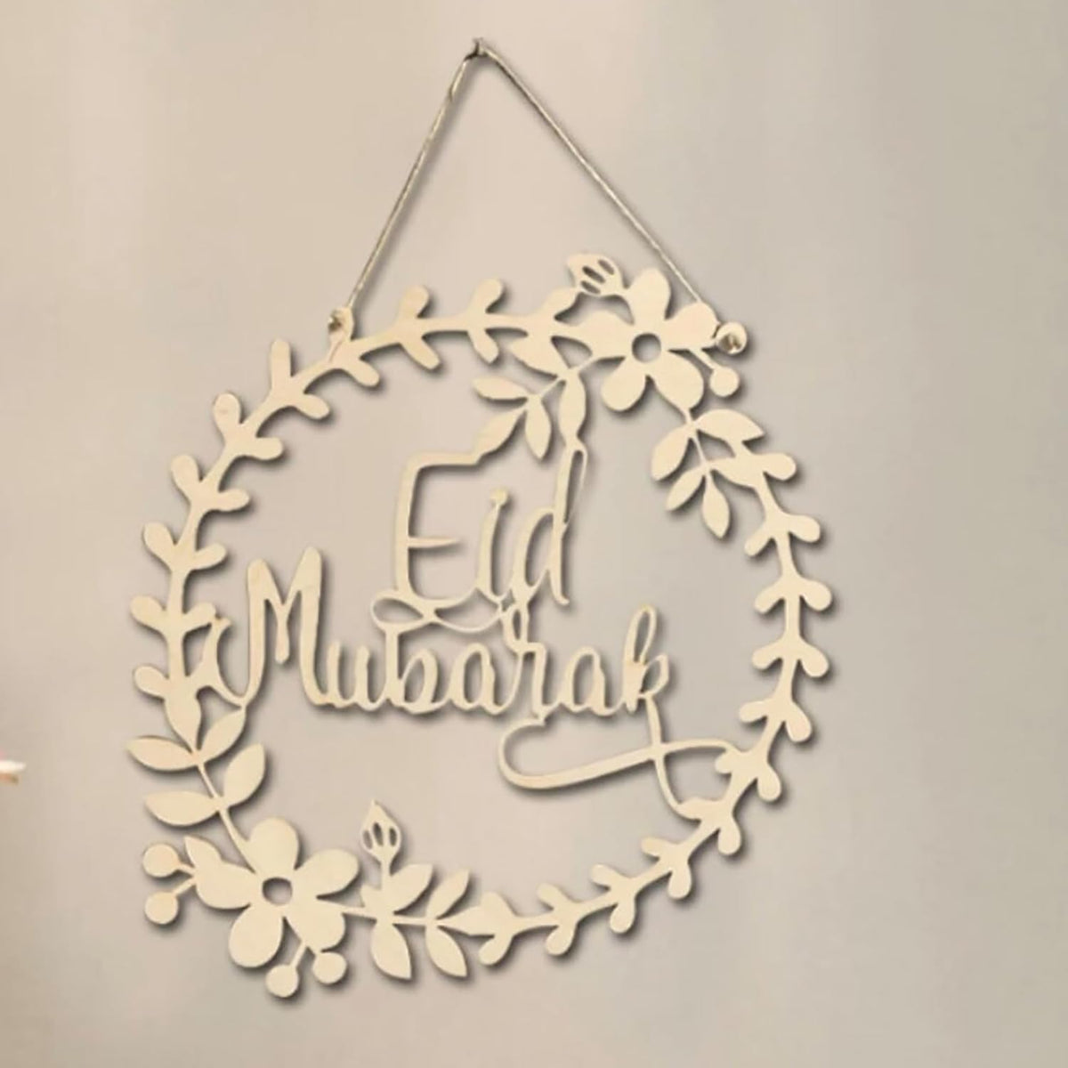 Decorative wall hanging with 'Eid Mubarak' text on a beige background