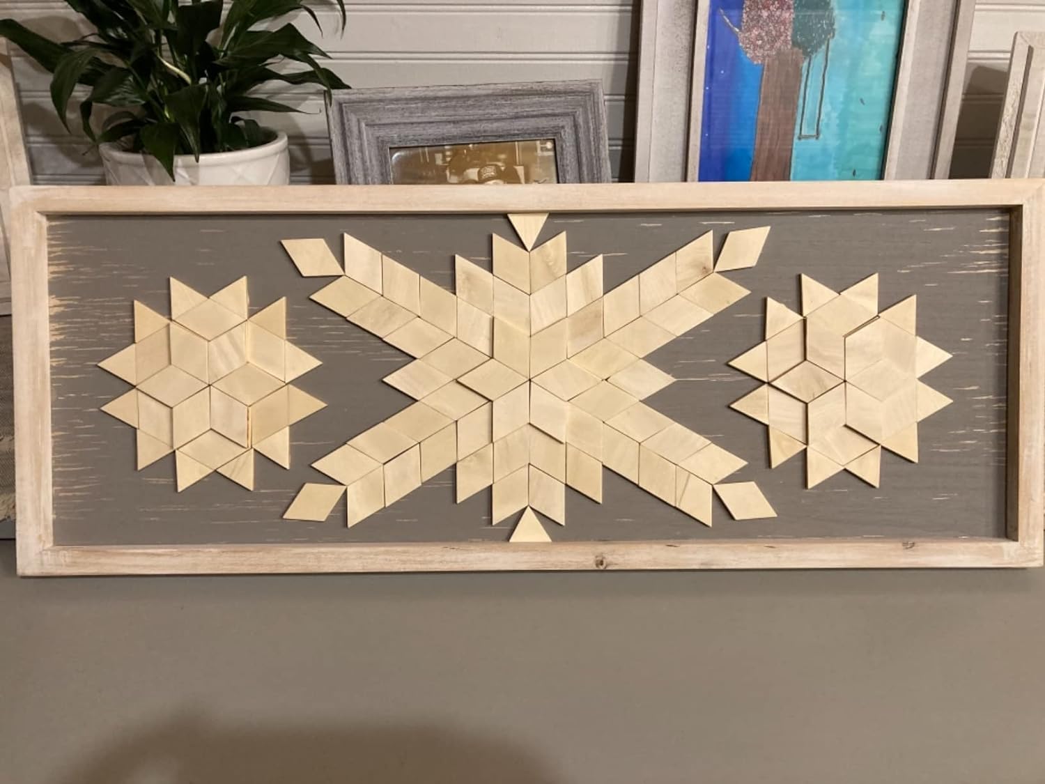 Decorative wall art with geometric patterns in a wooden frame.