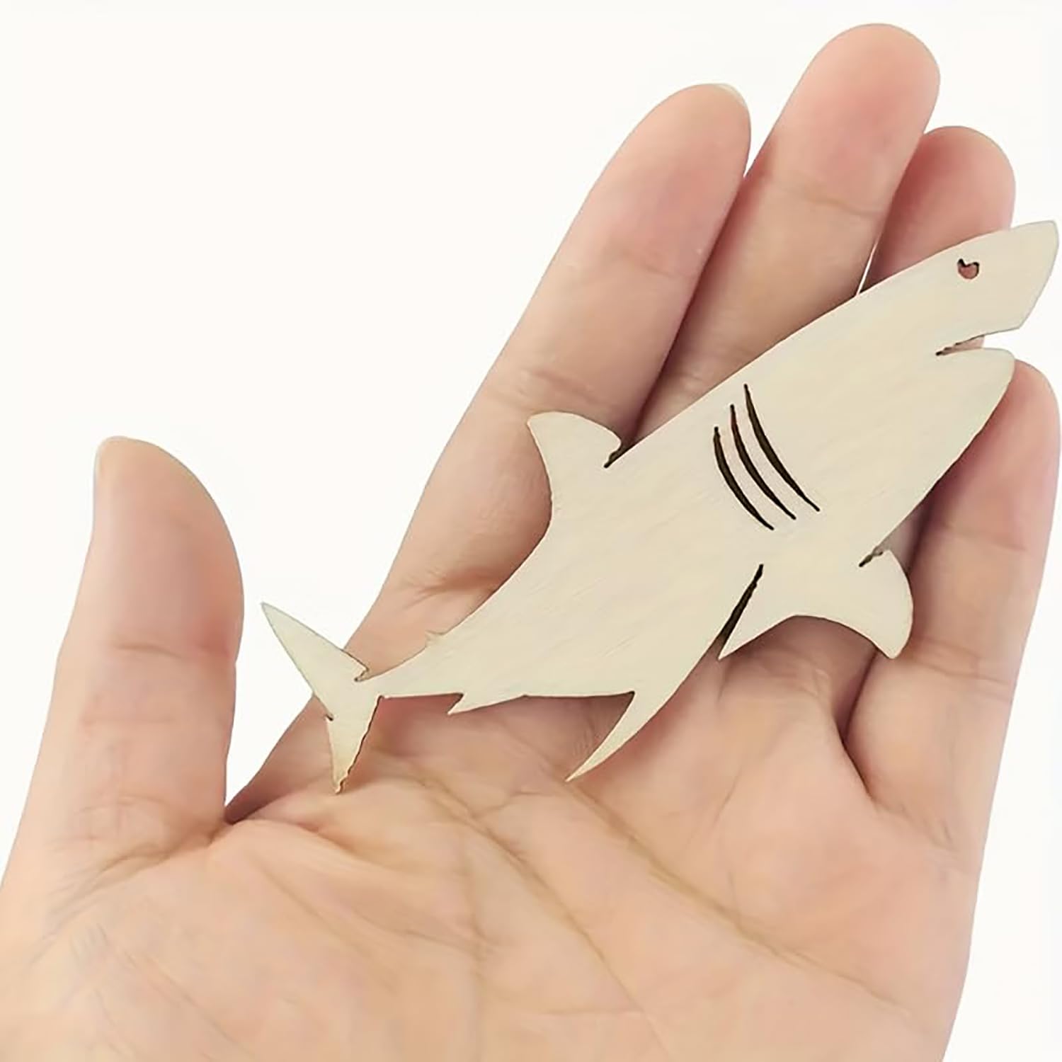 Wooden shark-shaped ornament held in a hand against a white background