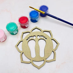 Decorative wooden piece with cut-out design, surrounded by paint containers and a brush on a light background.