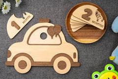 Wooden toy car and number cards on a textured surface with a frog toy in the corner.