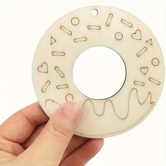 Wooden teething ring with geometric patterns held by a hand on a white background