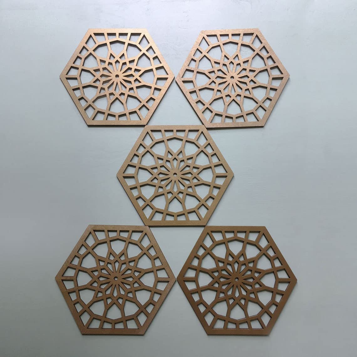 Four wooden hexagonal coasters with intricate cut-out patterns on a light gray background