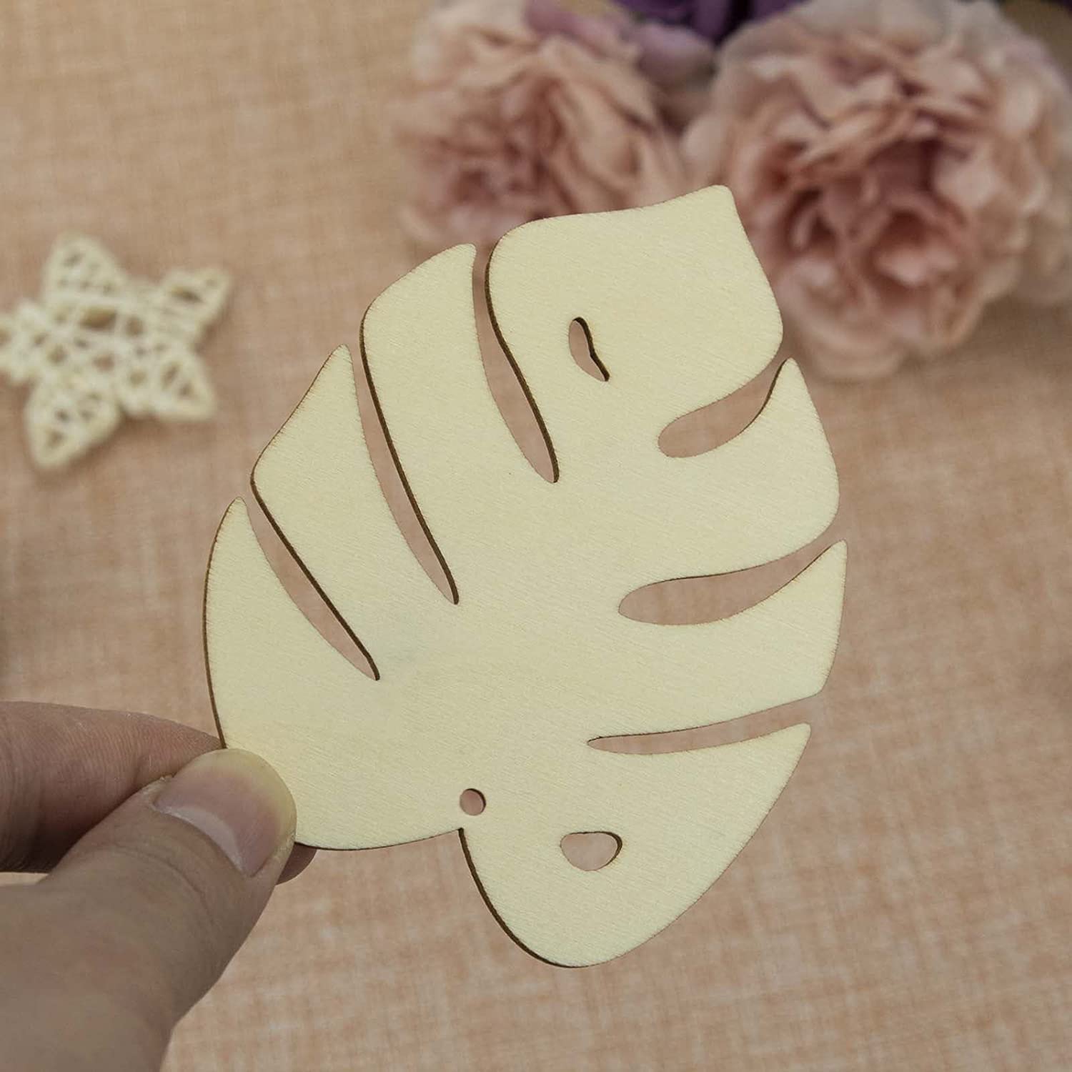 Hand holding a cut-out leaf shape against a floral background