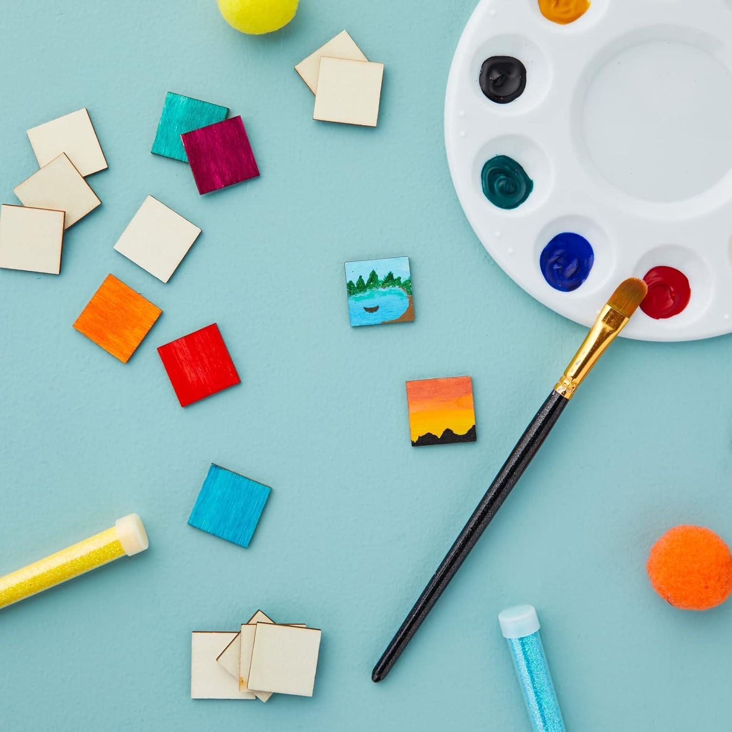 Art supplies including a paintbrush, color swatches, and a palette on a light blue background