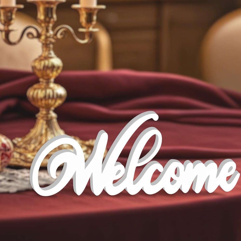 Decorative 'Welcome' sign on a table with a gold candlestick holder and red cloth.