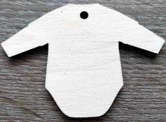 White baby onesie-shaped tag on a wooden surface