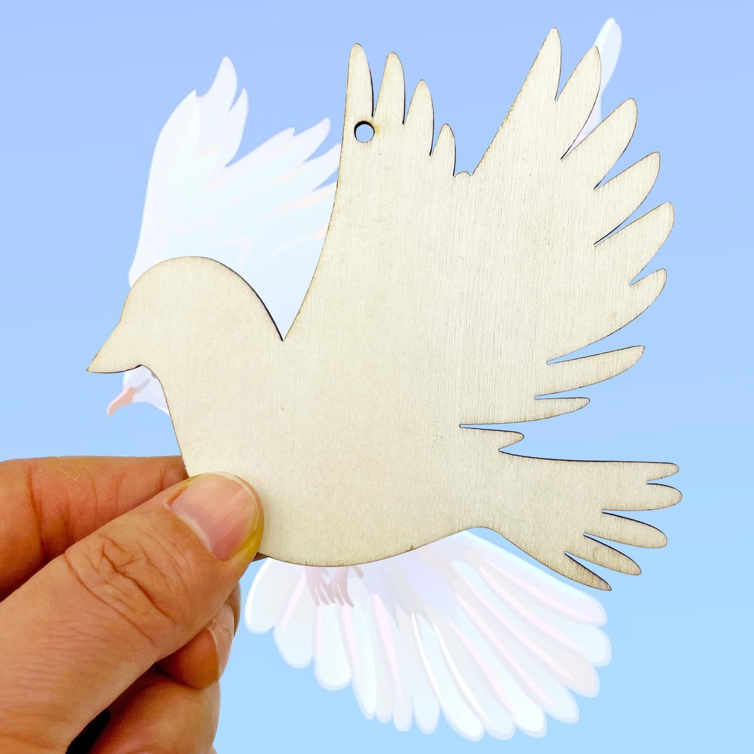 Wooden dove ornament held by a hand against a light blue background