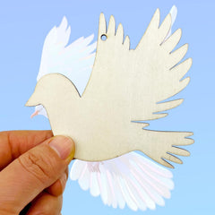 Wooden dove ornament held by a hand against a light blue background