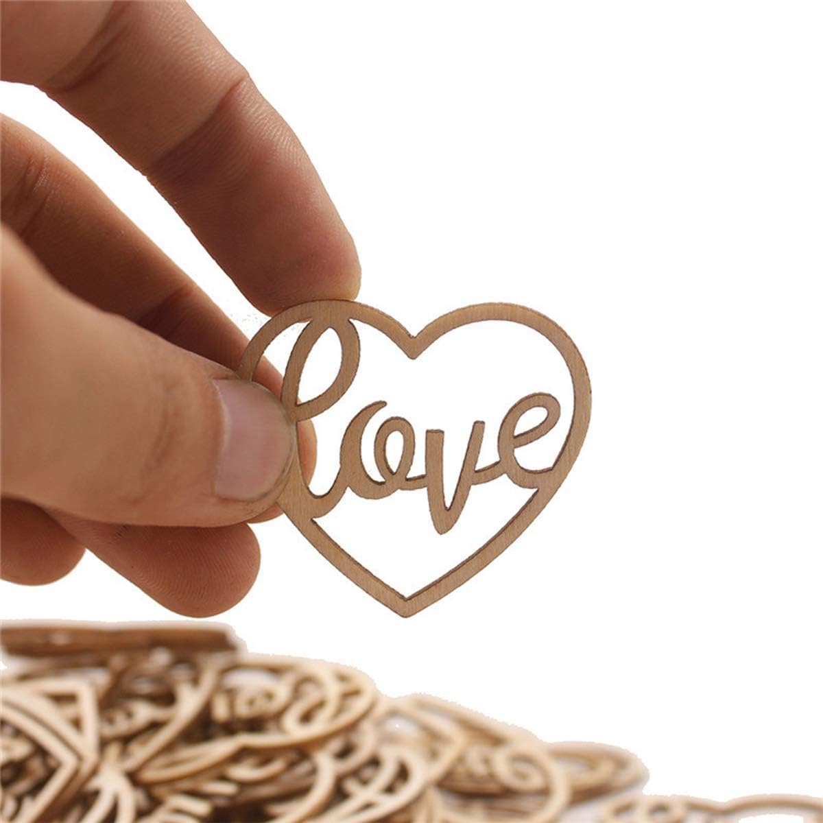 Heart-shaped wooden cutout with 'love' text held by a hand against a white background