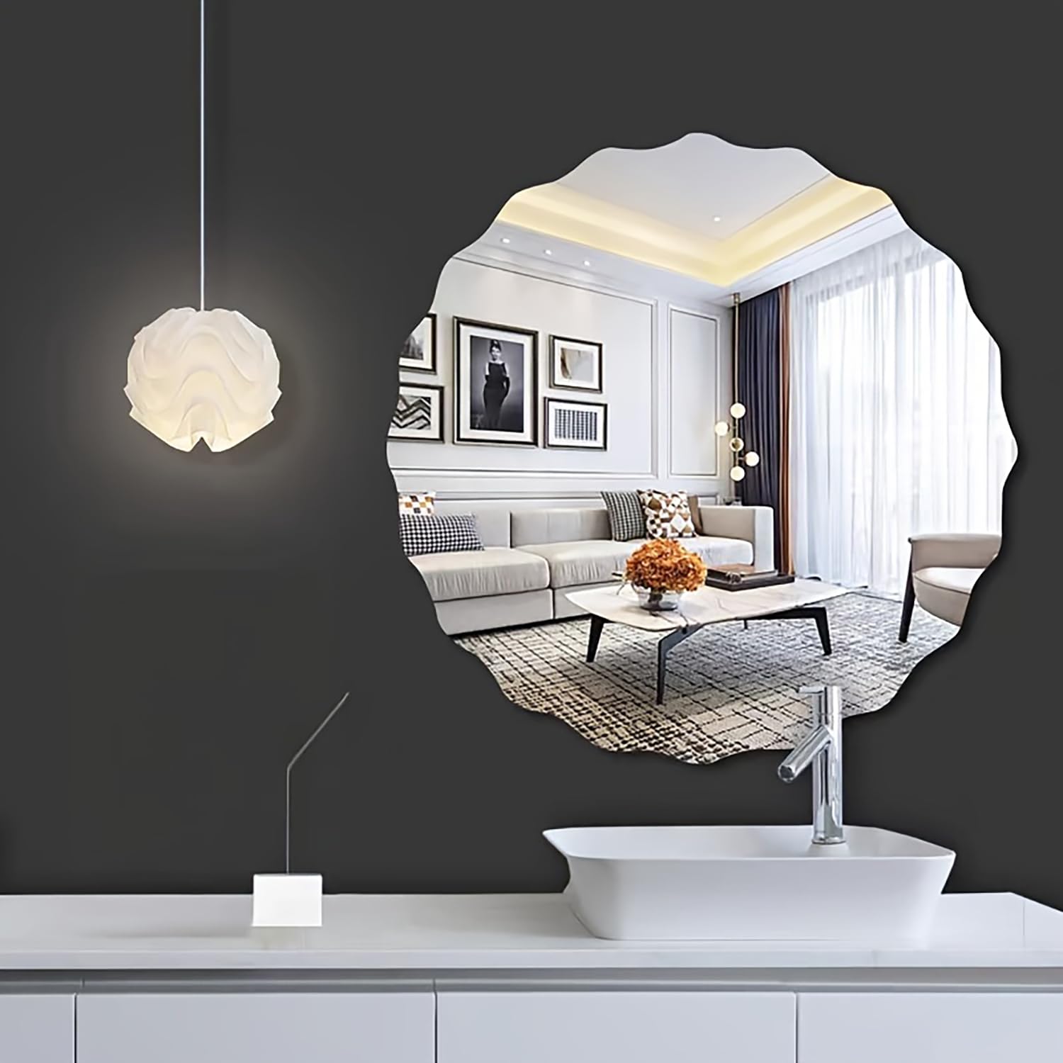 Round mirror reflecting a modern living room with a gray sofa and decorative elements.
