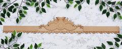 Decorative wooden border with intricate carvings on a white marble background with green leaves.