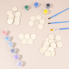 Hexagonal wooden pieces, paint containers, and brushes on a beige surface
