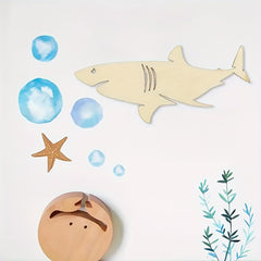 Wooden shark toy with bubbles, starfish, and seashell on a white background