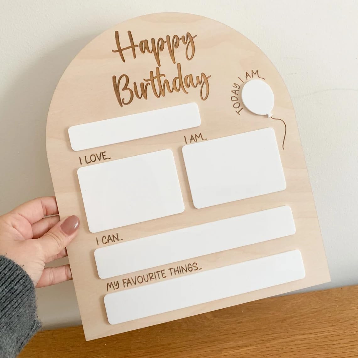 Birthday questionnaire card held by a hand on a wooden surface