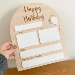 Birthday questionnaire card held by a hand on a wooden surface