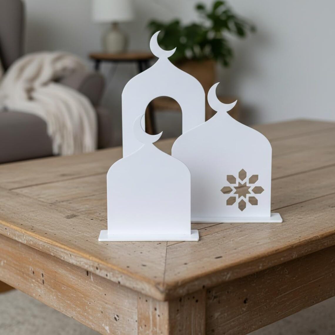 White decorative lanterns with moon and star designs on a wooden table.