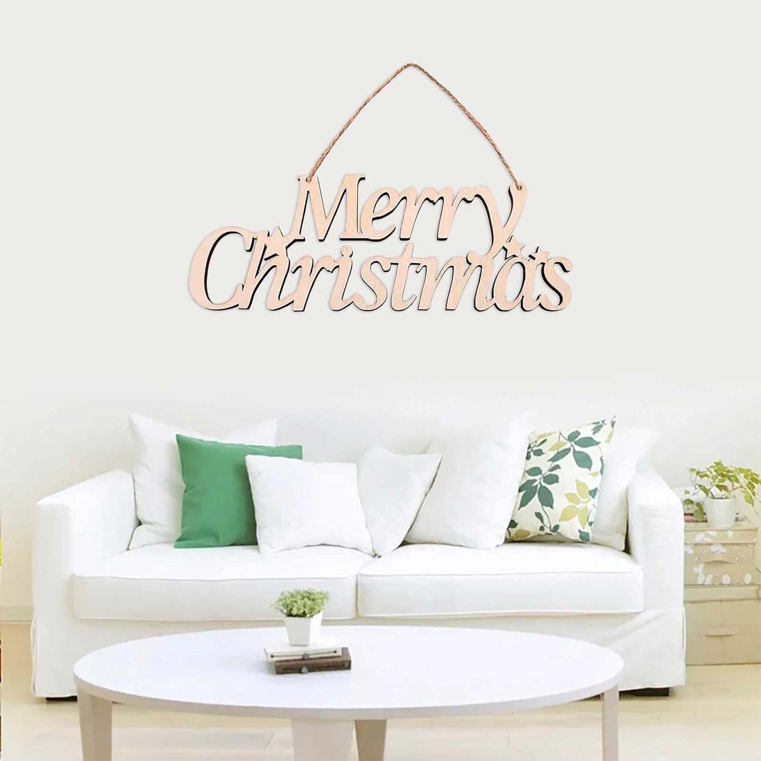 Wooden 'Merry Christmas' decoration hanging above a white sofa with decorative pillows.