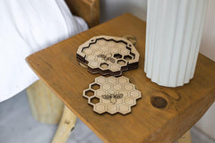 Hexagonal wooden coasters with honeycomb design on a wooden surface.