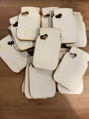 Stack of white paper tags with heart cutouts on a wooden surface