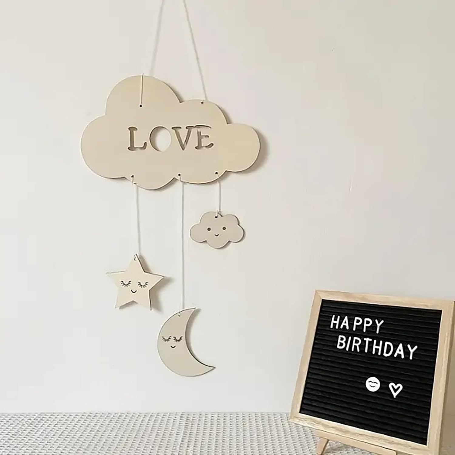 Decorative cloud with 'LOVE' and hanging stars, moon, and cloud on a light background.