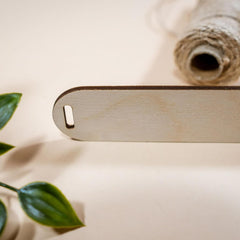 Wooden tool on a light surface with green leaves and a roll of twine.