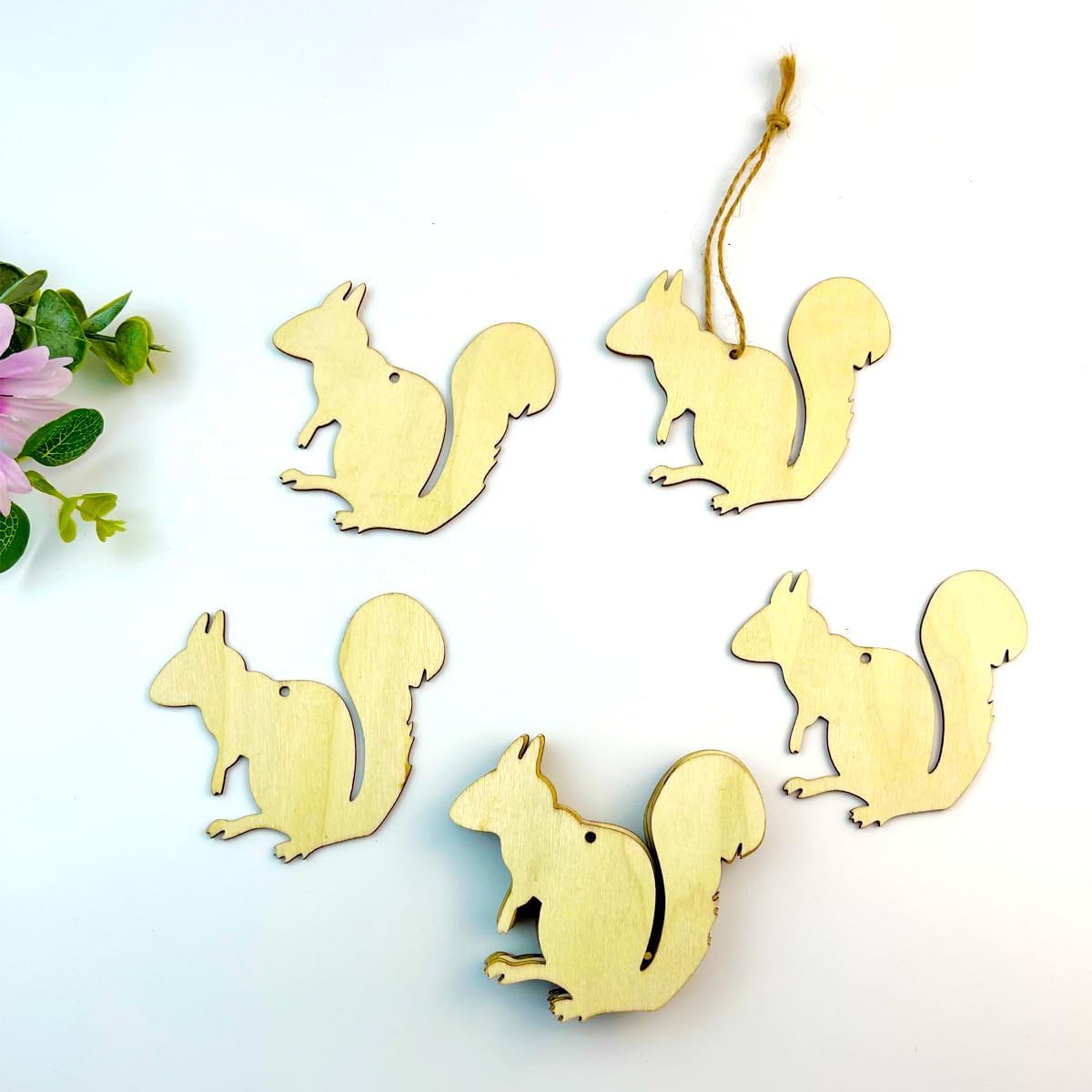 Gold squirrel-shaped ornaments on a white background with greenery.